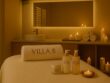 Luxury facial setup at Villa 8 Ladies Salon & Spa in Jumeirah, Dubai, featuring Maria Galland Paris skincare bottles, a towel pillow embroidered with ‘Villa 8,’ soft candlelight, and elegant beige and gold spa décor