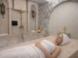 Luxury hammam treatment at Villa 8 Ladies Salon & Spa in Jumeirah, showing a woman relaxing on a traditional flat marble hammam bed in a private Moroccan-inspired spa setting